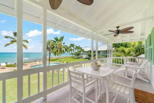 a white porch with a table and chairs and the ocean at Renovated, Oceanfront 2bd Seven Mile Beach Condo with amazing views in George Town