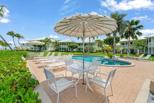 a table with chairs and an umbrella next to a pool at Renovated, Oceanfront 2bd Seven Mile Beach Condo with amazing views in George Town