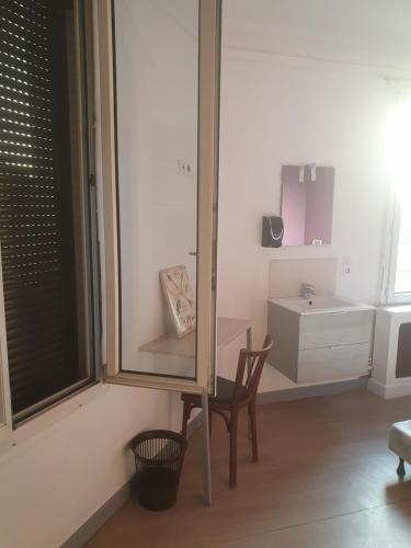 Habitación con espejo, silla y mesa. en Aux Bons Amis en Reims