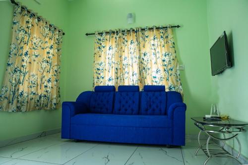 Sofá azul en la sala de estar con cortinas en DREAMS VILLA Near Rajagiri Hospital, en Alwaye