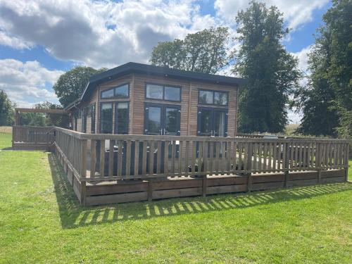 a small house with a wooden fence in the grass at Glasshouse hot tub lodge in Hengrave
