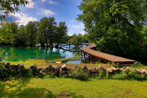 uma ponte de madeira sobre um rio com um lago verde em Apartman Bucko em Bihać
