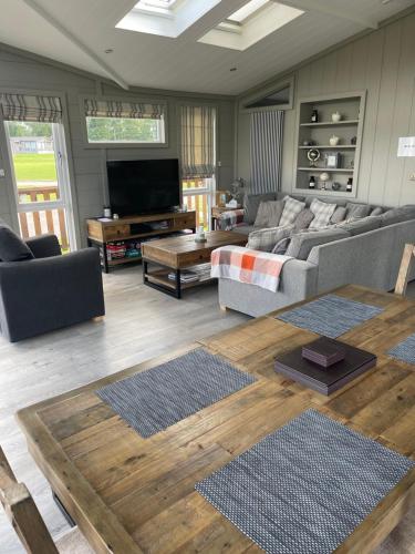 a living room with a couch and a table at Glasshouse hot tub lodge in Hengrave