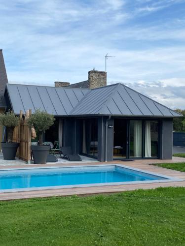 une maison avec une piscine en face de celle-ci dans l'établissement LE CLOS DAUPHINAIS Chez Laurette, à Quévert