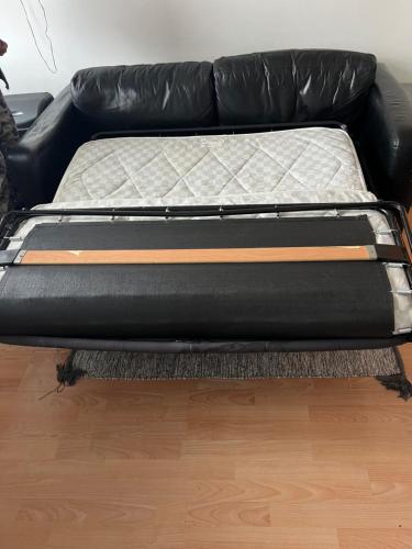 a black couch sitting on top of a wooden floor at Luton Airport £40 per night, best value in Luton