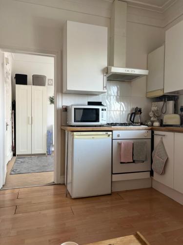 a kitchen with white cabinets and a microwave at Luton Airport £40 per night, best value in Luton
