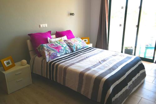 1 dormitorio con 1 cama con almohadas rosas y moradas en Apartamento Quinta Nova, en Alvor