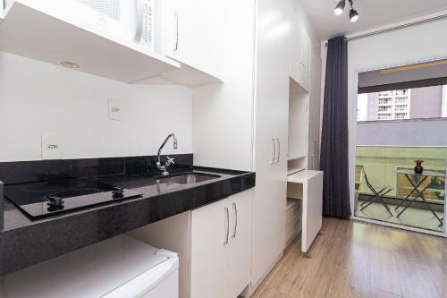a kitchen with white cabinets and a sink and a window at Vossa Bossa VN Turiassu in Sao Paulo