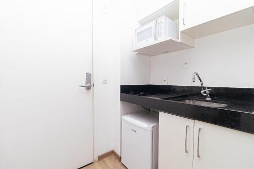 a white kitchen with a sink and a microwave at Vossa Bossa VN Turiassu in Sao Paulo