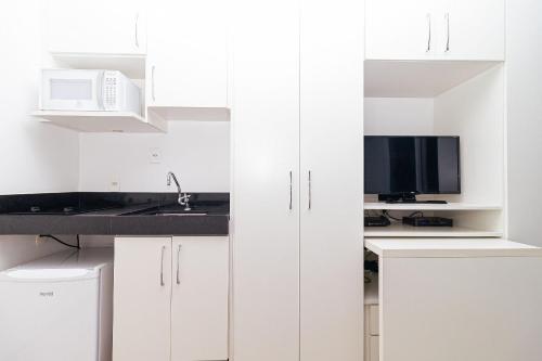 a white kitchen with white cabinets and a microwave at Vossa Bossa VN Turiassu in Sao Paulo