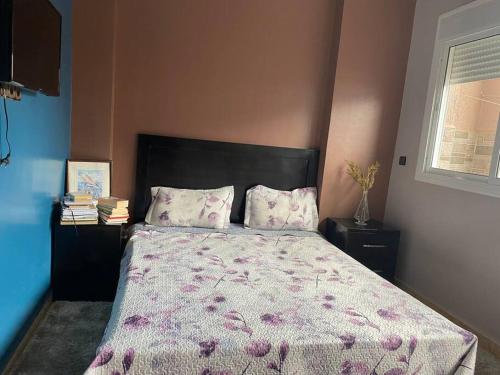 um quarto com uma cama com um edredão roxo e almofadas em Cozy apartment in Ksar el kebir em Ksar el Kebir