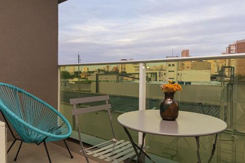 a table and chairs on a balcony with a vase of flowers at Vossa Bossa VN Turiassu in Sao Paulo