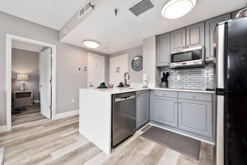 a kitchen with white cabinets and a black refrigerator at Apartment with Volcano Bay view in Orlando