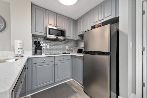 a kitchen with white cabinets and a stainless steel refrigerator at Apartment with Volcano Bay view in Orlando