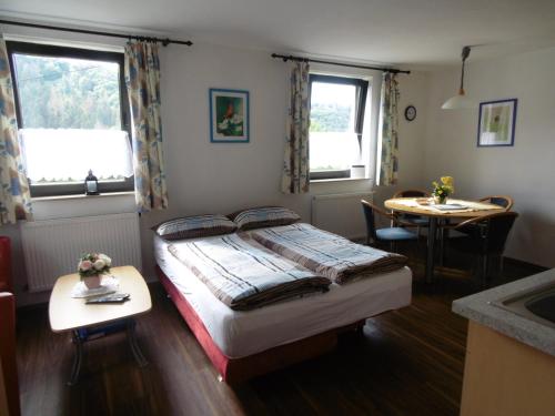 a bedroom with a bed and a table and two windows at Ferienwohnung Schäfer in Waldbreitbach