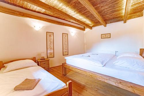 two twin beds in a room with wooden ceilings at Farma Zelená Ruža in Kľačno