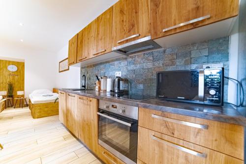 a kitchen with wooden cabinets and a microwave at Farma Zelená Ruža in Kľačno