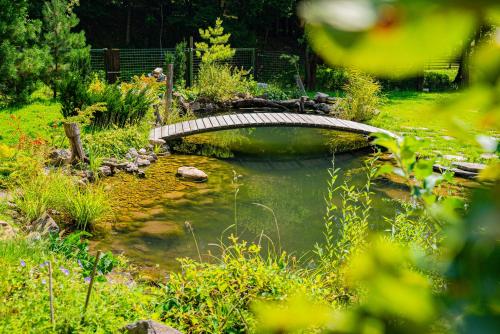 a bridge over a pond in a garden at Farma Zelená Ruža in Kľačno