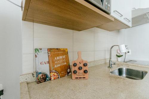 a kitchen counter with a book and a sink at Super bem localizado, no centro, com varanda! in Poços de Caldas