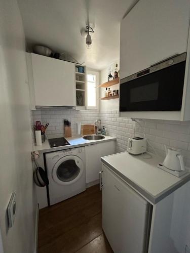una pequeña cocina con lavadora y fregadero en Big Luxury Studio in the heart of St-Germain, en París