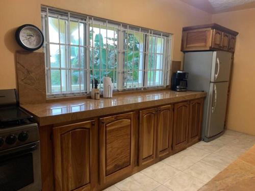 a kitchen with wooden cabinets and a refrigerator at Full 3 BD Home w/Oceanviews and AC in all rooms. in Manchioneal