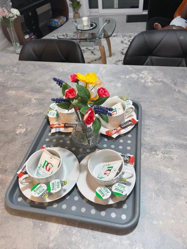 a tray with plates and flowers on a table at Vileto apartment in central Bournemouth in Bournemouth