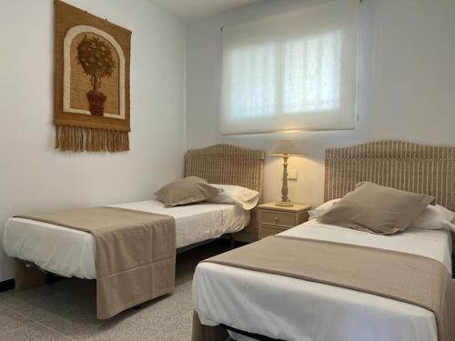 1 dormitorio con 2 camas, lámpara y ventana en Apartamento 1ª Línea de Playa - Con Piscina y Parking, en Gandía