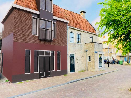 een rood-wit gebouw op een straat bij Stadshotel DE ACADEMIE in Franeker