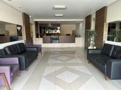 a waiting room with leather couches and a bar at Palace Hotel in Itajubá