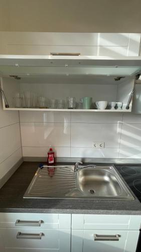 a kitchen with a stainless steel sink and white cabinets at Apartment am Zollverein -WiFi - Parking for free in Essen