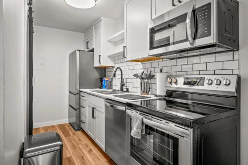 uma cozinha com electrodomésticos de aço inoxidável e armários brancos em Cozy Condo Near Downtown! em Louisville