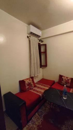 Cette chambre comprend 2 lits rouges et une table. dans l'établissement Résidence gharnata D5, à Marrakech