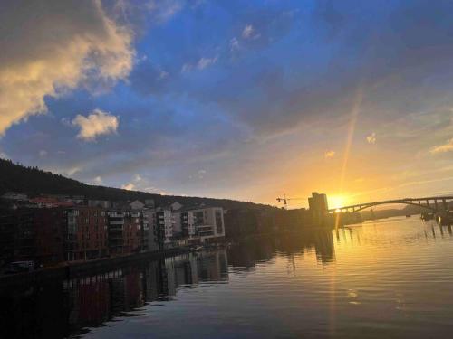 a sunset over a body of water with a bridge at Sentrums-nær leilighet med sjøutsikt og takterasse in Bergen