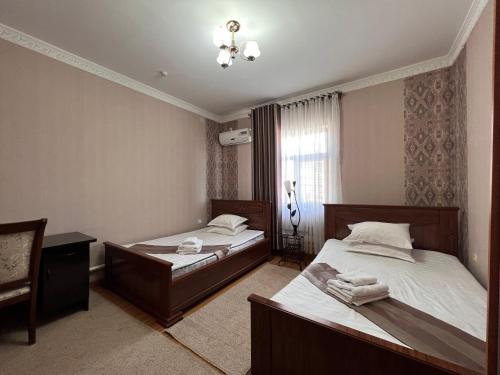 um quarto com 2 camas e uma janela em MASSAGET HOTEL em Nukus