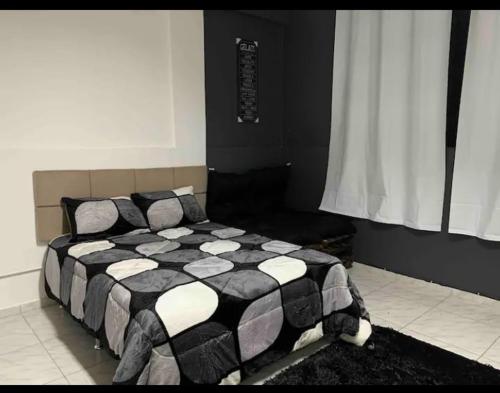 a bedroom with a black and white comforter on a bed at Studio Próximo Aeroporto Passo Fundo in Passo Fundo