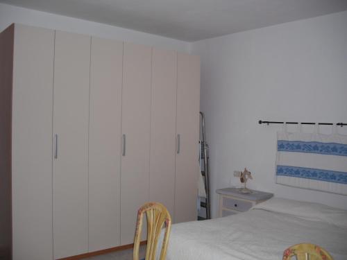 a bedroom with white cabinets and a bed with two chairs at Casa Vacanze Il Pino in Cannigione
