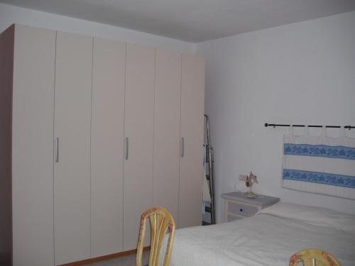 una camera da letto con armadi bianchi e un letto con due sedie di Casa Vacanze Il Pino a Cannigione