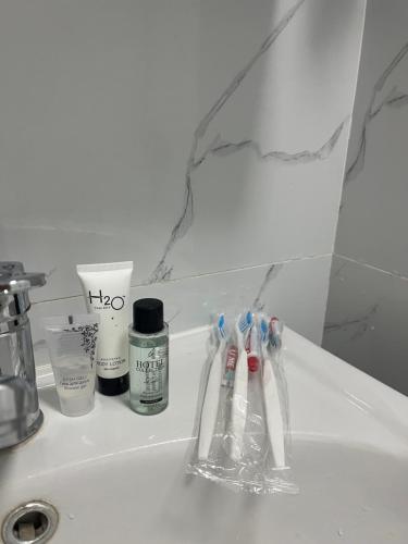 a bathroom sink with toothbrushes and other items on it at Отличная квартира со всеми удобствами. in Almaty