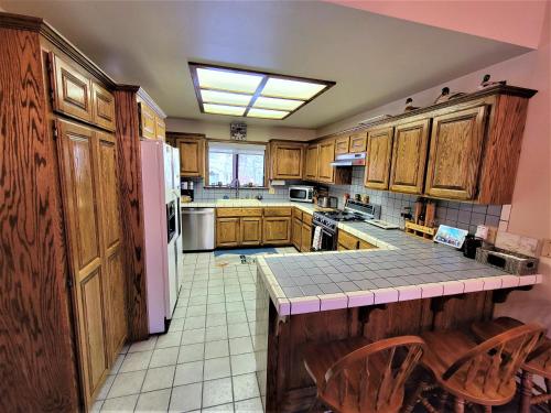 a kitchen with wooden cabinets and a white refrigerator at Four Seasons Getaway-Private Hot Spa with Pine Tree Views-Walk to Village and Pineknot Trailhead-Plus King Bed! in Big Bear Lake