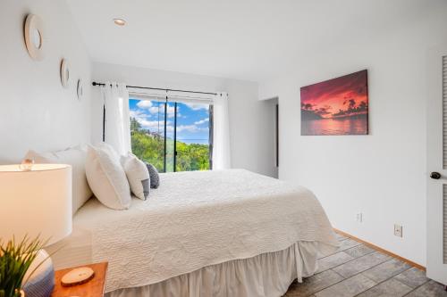 a white bedroom with a bed and a window at SeaLodge B8 in Princeville