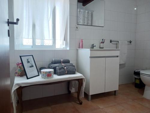 a bathroom with a bench with a sink and a toilet at Casa dos pássaros in Carril