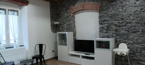 sala de estar con TV y pared de piedra. en A UN PASSO DAL MARE, en Riva Trigoso
