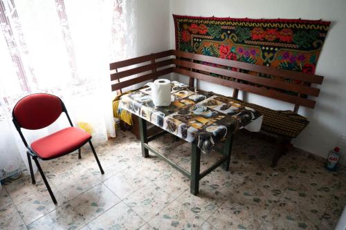 a table and a chair in a room with a bench at Cabana La Buligă in Armeniş