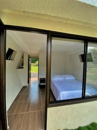 um quarto com uma cama e algumas janelas de vidro em Cielo Abierto Glamping em San Gil