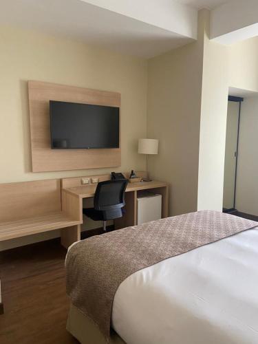 a hotel room with a bed and a desk with a television at Del Prado Hotel in Lima