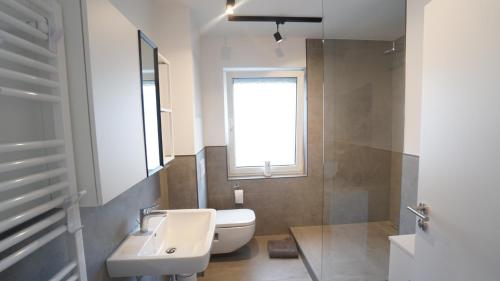 baño con lavabo y aseo y ventana en ferienwohnung-senne Apartment Romeo, en Schloss Holte-Stukenbrock