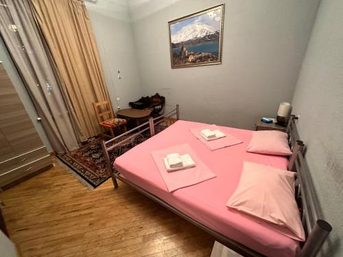 a small room with a pink bed with two tables at Bridge House Yerevan Armenia in Yerevan