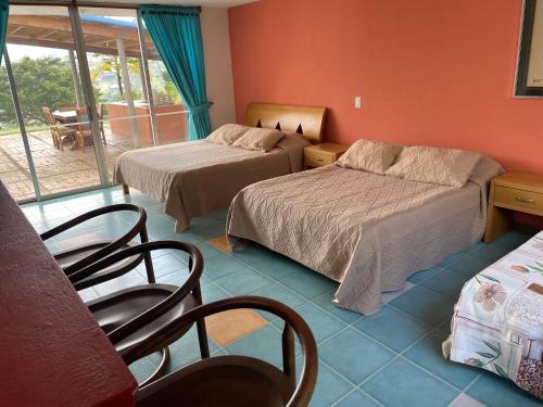 a hotel room with two beds and a balcony at Hotel Familiar El Remanso Del Agua in Guatapé