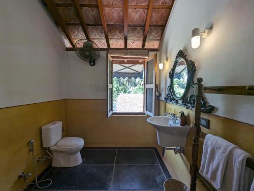 een badkamer met een toilet, een wastafel en een raam bij Thanga House by LuxUnlock Private Villas in Tarangambādi