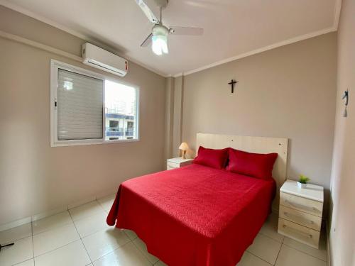 um quarto com uma cama vermelha e uma cruz na janela em Residencial Santo Expedido na Praia Grande